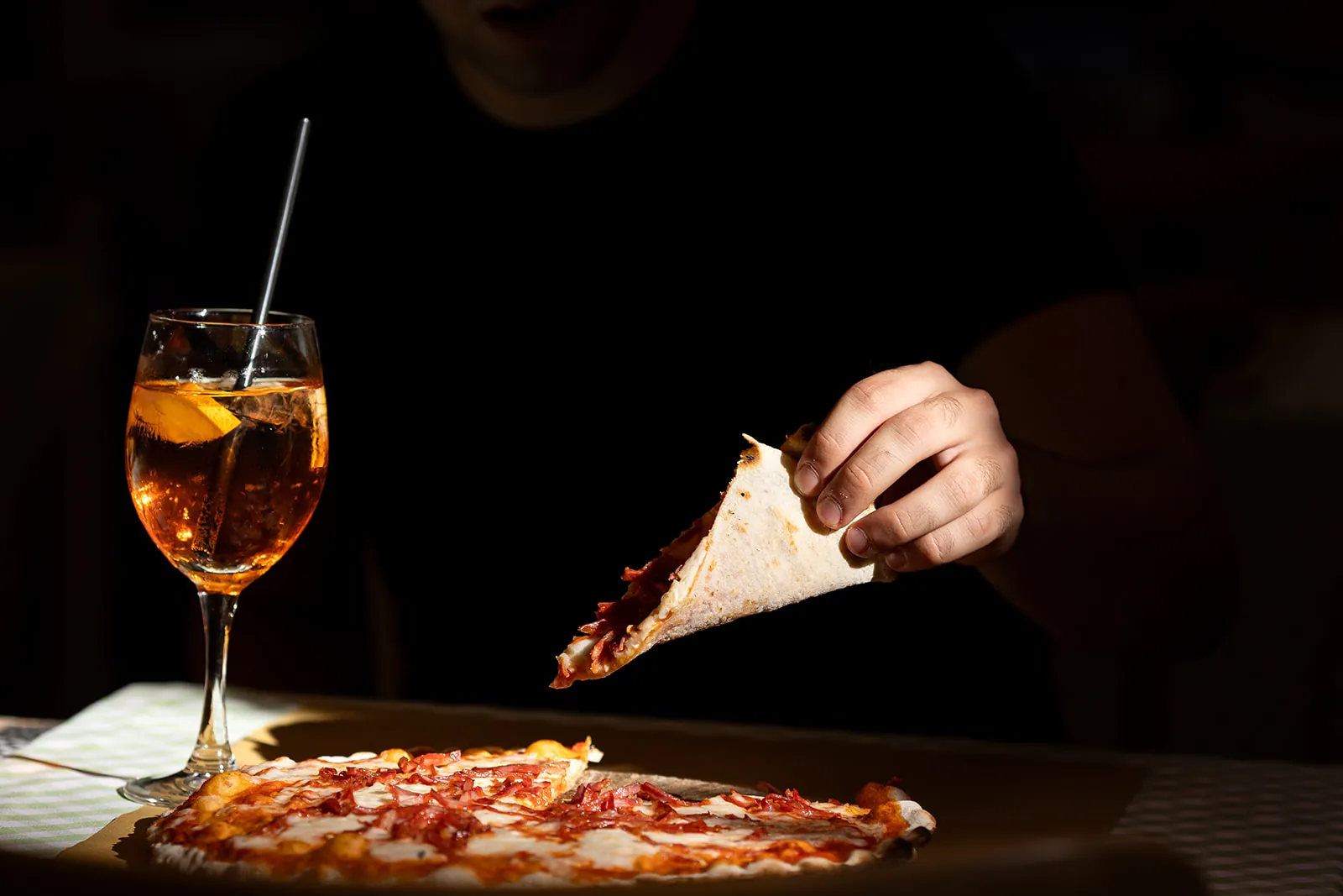 Una fetta di pizza e uno spritz